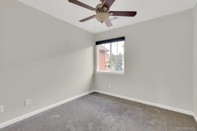 an empty room with a window and a fan