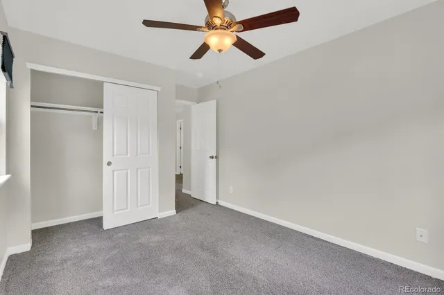 an empty room with closet and a chandelier fan