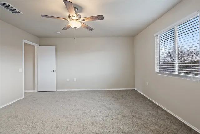 an empty room with windows and fan