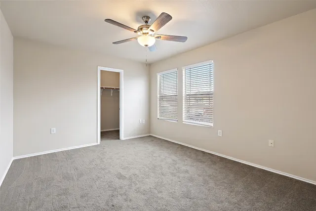 an empty room with windows and fan