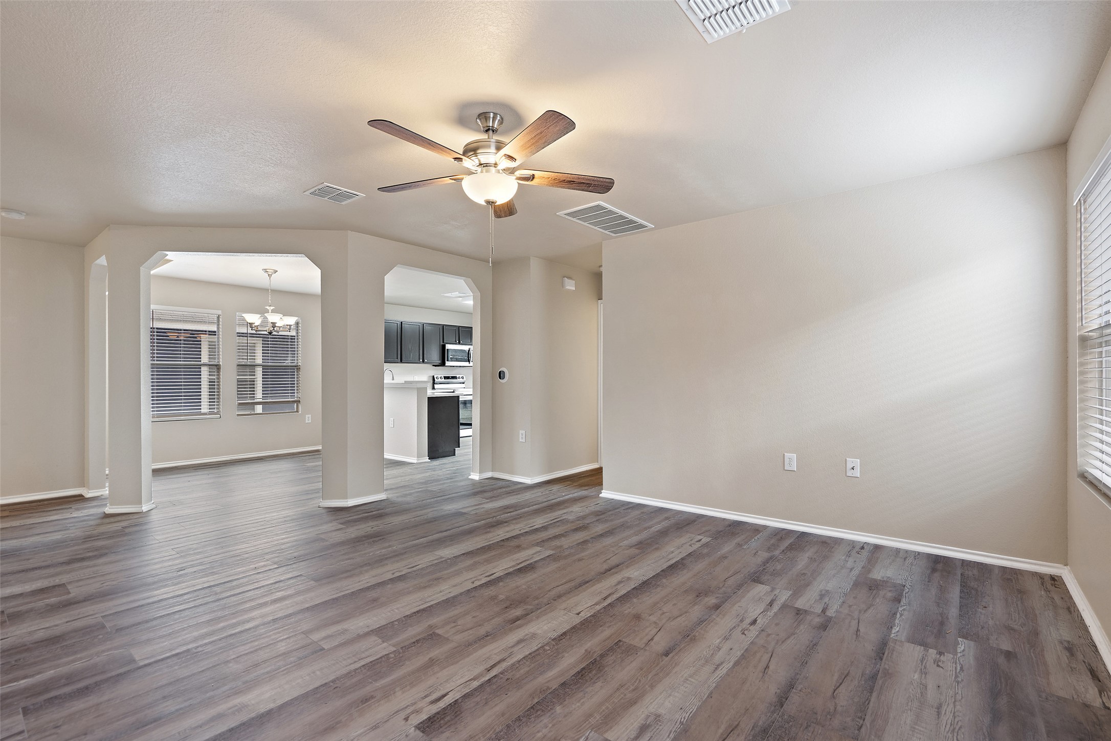 1617 Anise Drive Austin, TX 78741 - Photo 7 of 35 Unfurnished living room featuring a chandelier, arched walkways, a ceiling fan, and dark wood-type flooring