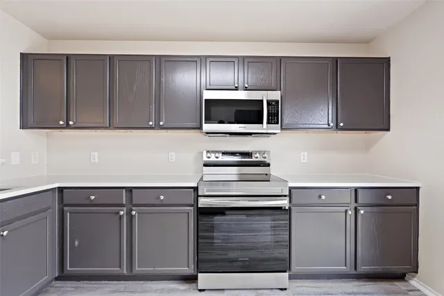 a kitchen with cabinets stainless steel appliances and wooden floor
