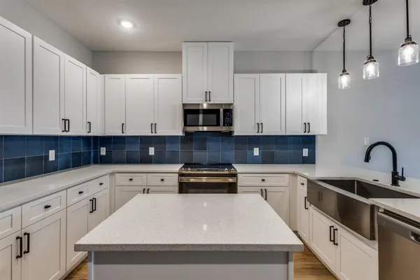a kitchen with granite countertop white cabinets and stainless steel appliances