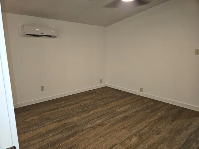 an empty room with wooden floor and ceiling fan