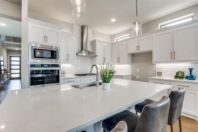 a kitchen with stainless steel appliances a white table chairs refrigerator and microwave