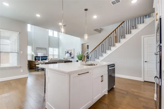 a kitchen with kitchen island a stove a sink a center island and wooden floor