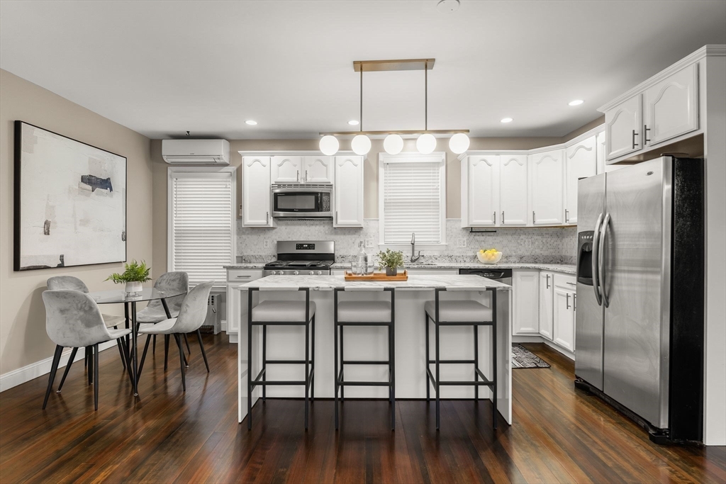77 Wheatland Street, Unit 2 Somerville, MA 02145 - Photo 8 of 20 a kitchen with kitchen island white cabinets and stainless steel appliances
