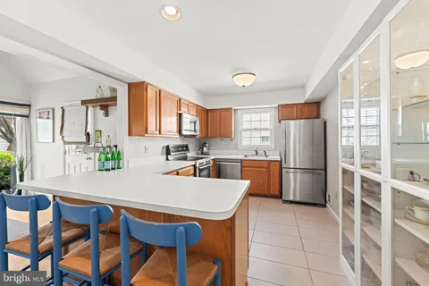a kitchen with stainless steel appliances a refrigerator a stove a dining table and chairs