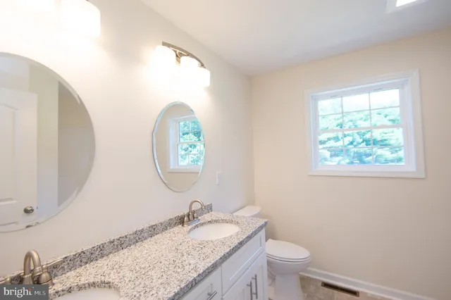 a bathroom with a granite countertop toilet a sink and a mirror