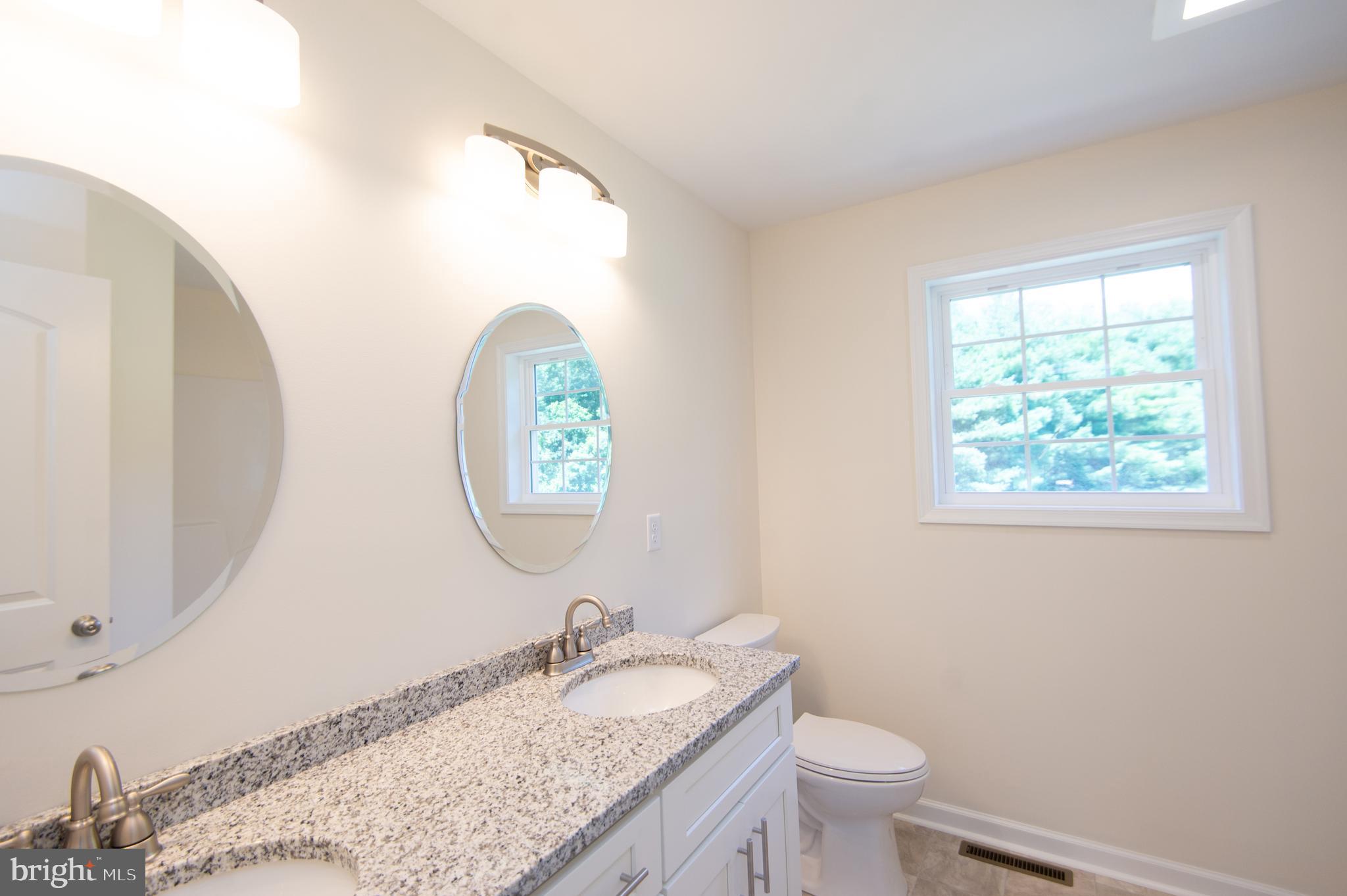 6706 Jayar Way Hurlock, MD 21643 - Photo 11 of 19 a bathroom with a granite countertop toilet a sink and a mirror