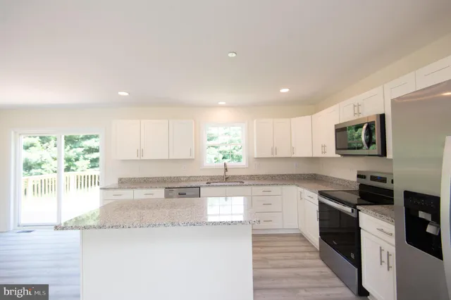 a kitchen with granite countertop white cabinets and stainless steel appliances