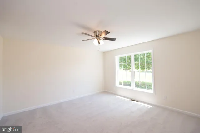 an empty room with a window and a ceiling fan
