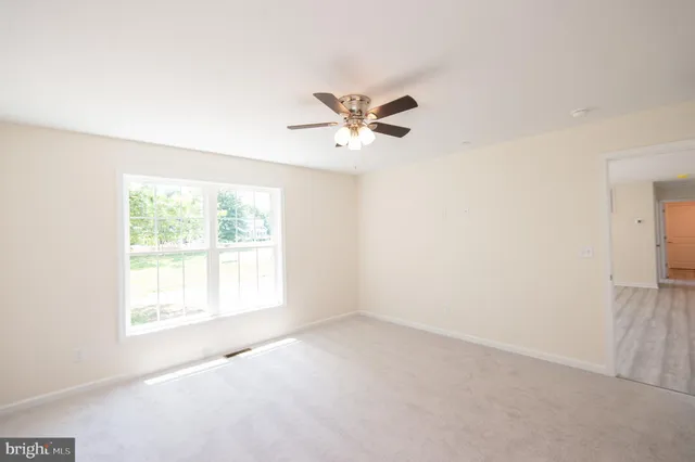 an empty room with a window and a ceiling fan
