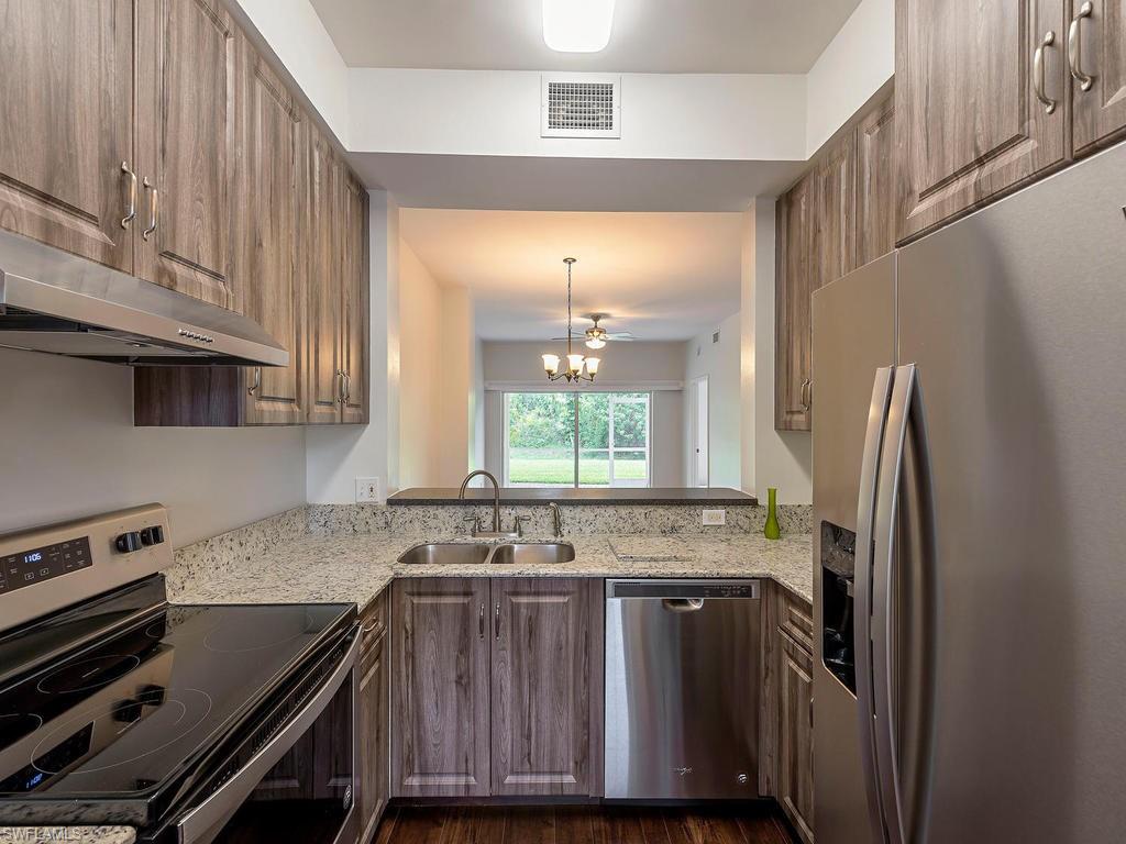 a kitchen with granite countertop a refrigerator a sink and cabinets