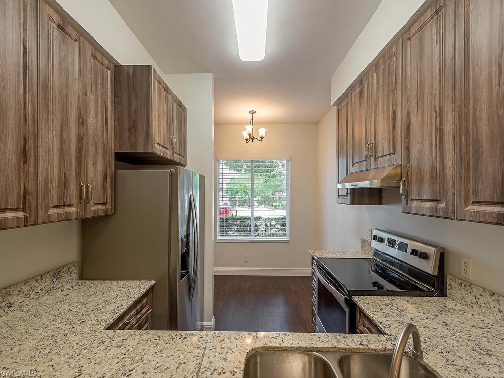 5470 16th Place Southwest, Unit 103 Naples, FL 34116 - Photo 4 of 12 a kitchen with wooden cabinets a sink a stove and a window