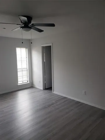 an empty room with wooden floor a ceiling fan and windows