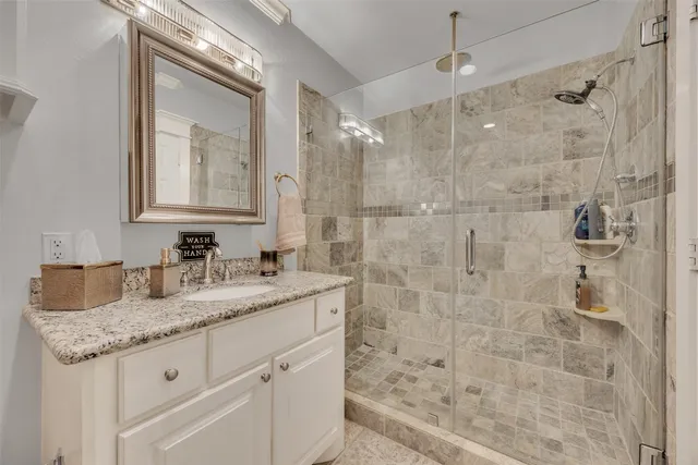 a bathroom with a granite countertop sink a mirror and shower