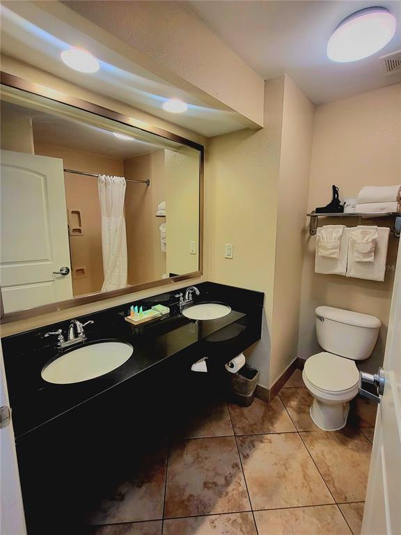 3000 Maingate Lane, Unit 517 Kissimmee, FL 34747 - Photo 9 of 13 a bathroom with a granite countertop toilet sink and mirror