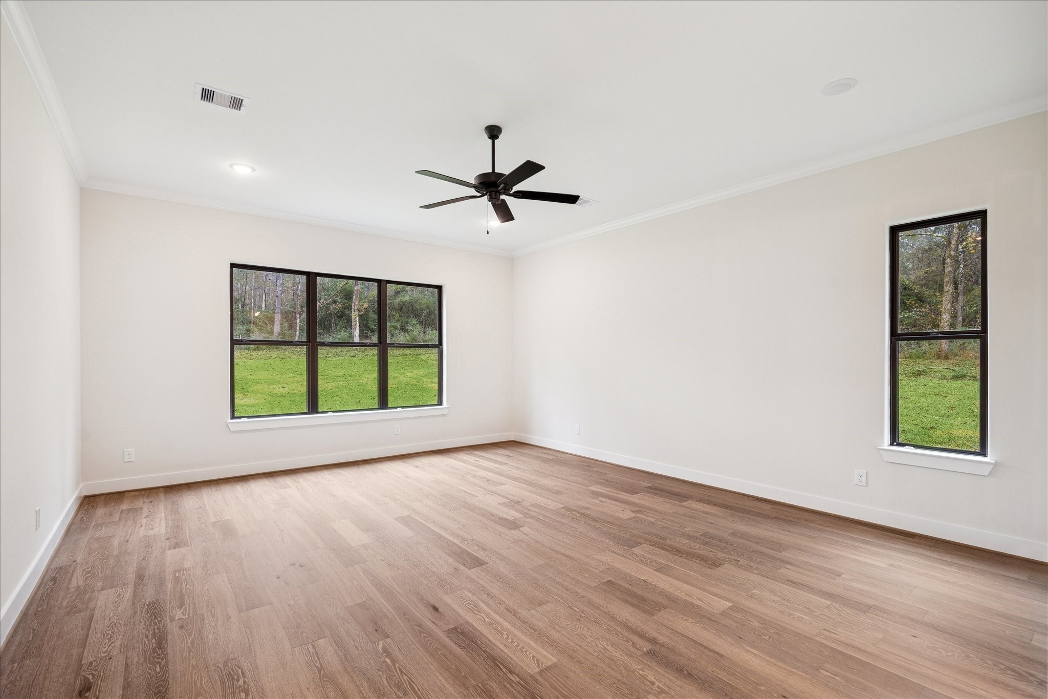104 Dawn Court Huntsville, TX 77340 - Photo 16 of 37 an empty room with wooden floor ceiling fan and windows