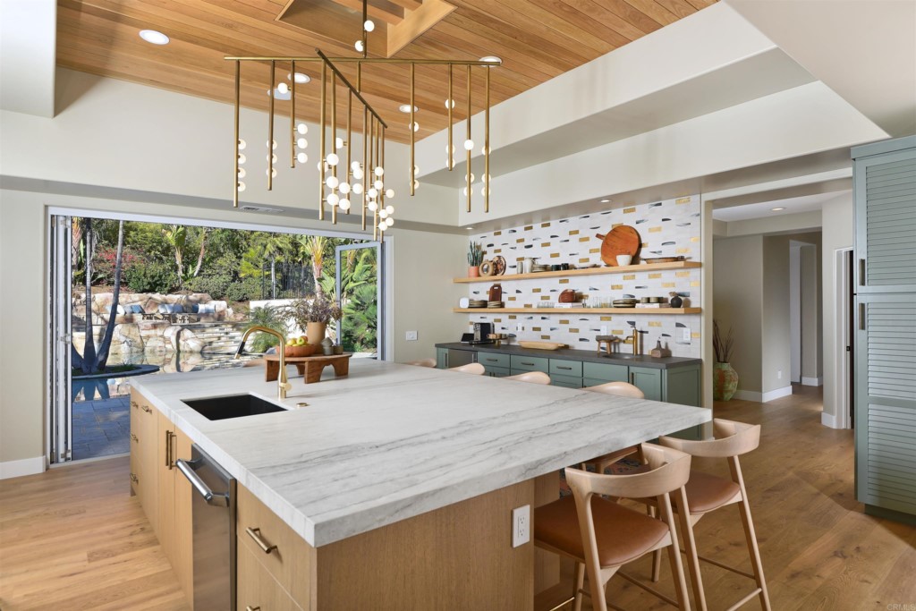 a kitchen with stainless steel appliances kitchen island granite countertop a table chairs and a wooden floor