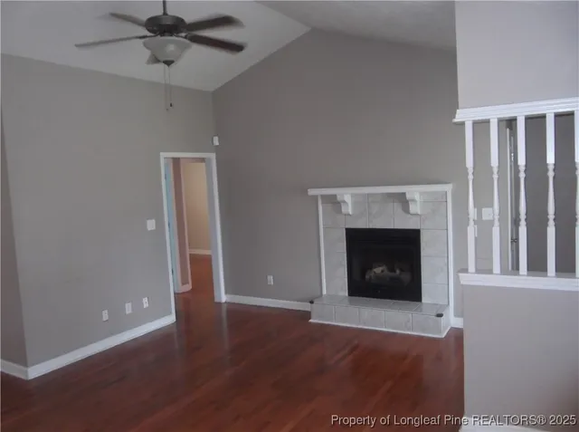 a view of an empty room with wooden floor and a fireplace