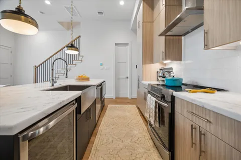 a kitchen with stainless steel appliances a dining table chairs and wooden floor