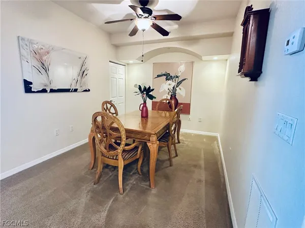 a dining room with furniture and a chandelier fan