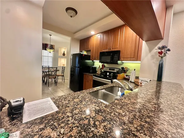a kitchen with stainless steel appliances granite countertop a refrigerator stove top oven dining table and chairs