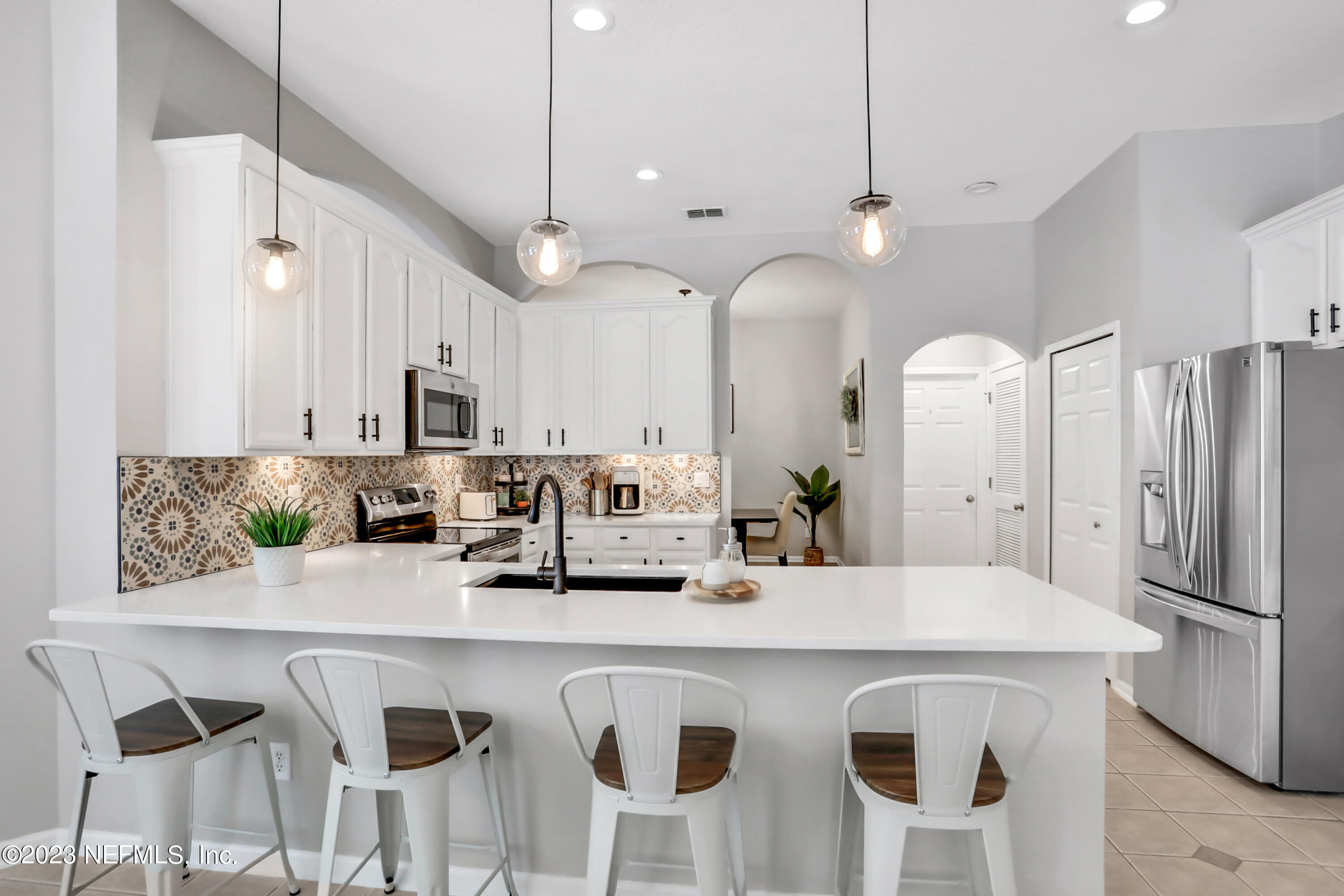 4100 Lonicera Loop St. Johns, FL 32259 - Photo 12 of 65 a kitchen with stainless steel appliances kitchen island granite countertop a refrigerator a sink a dining table and chairs with wooden floor
