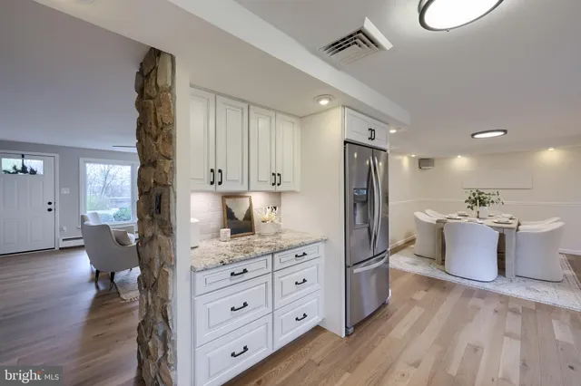 a kitchen with kitchen island granite countertop a refrigerator oven a sink dishwasher and white cabinets with wooden floor