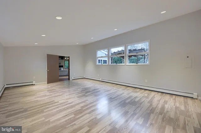 an empty room with wooden floor and windows