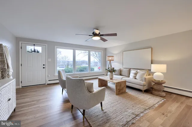 a living room with furniture a large window and wooden floor
