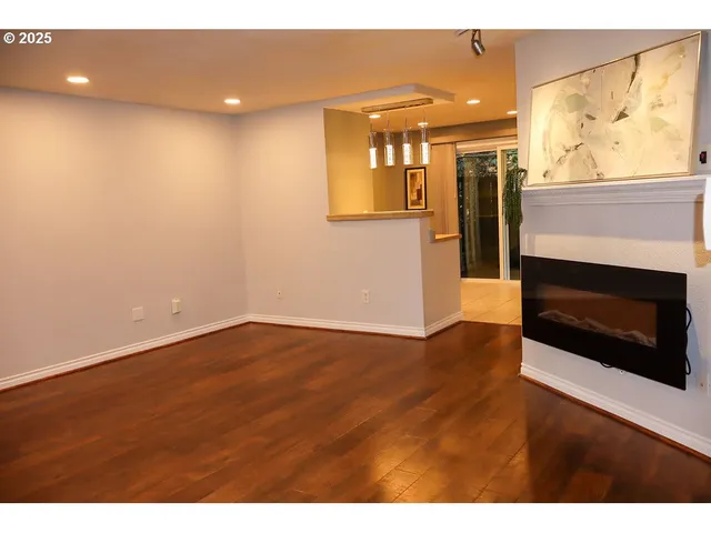 a view of an empty room with wooden floor and a fireplace