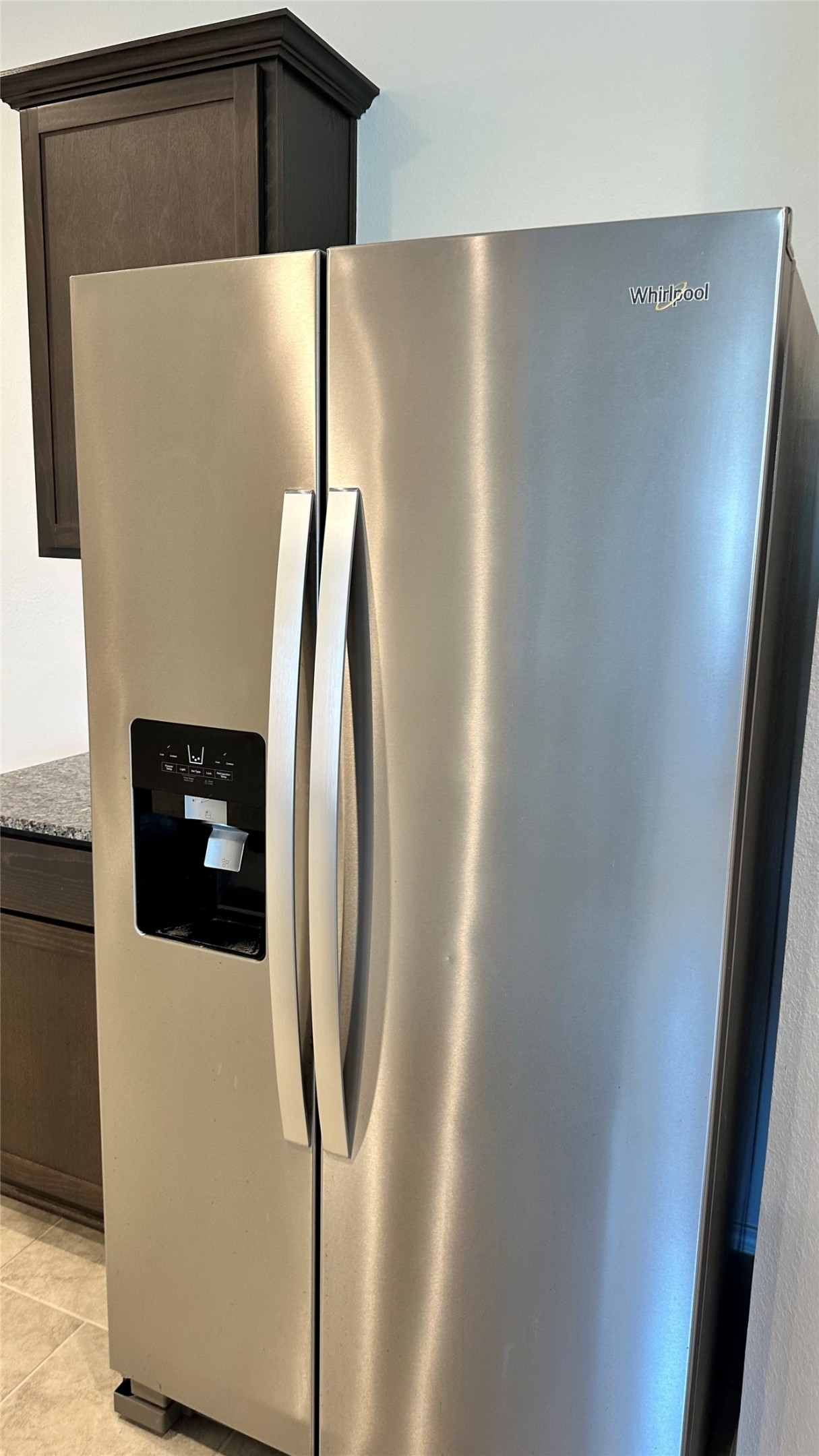 1103 Cattle Chute Court Rosharon, TX 77583 - Photo 17 of 26 Sleek stainless steel side-by-side refrigerator with water and ice dispenser, adjacent to dark wood cabinetry and granite countertops, offering a modern kitchen touch.