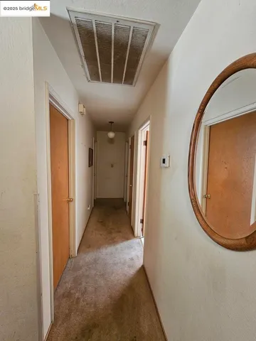 a view of a hallway with wooden floor and a bathroom