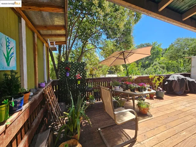 a view of a patio with table and chairs potted plants with wooden floor and fence