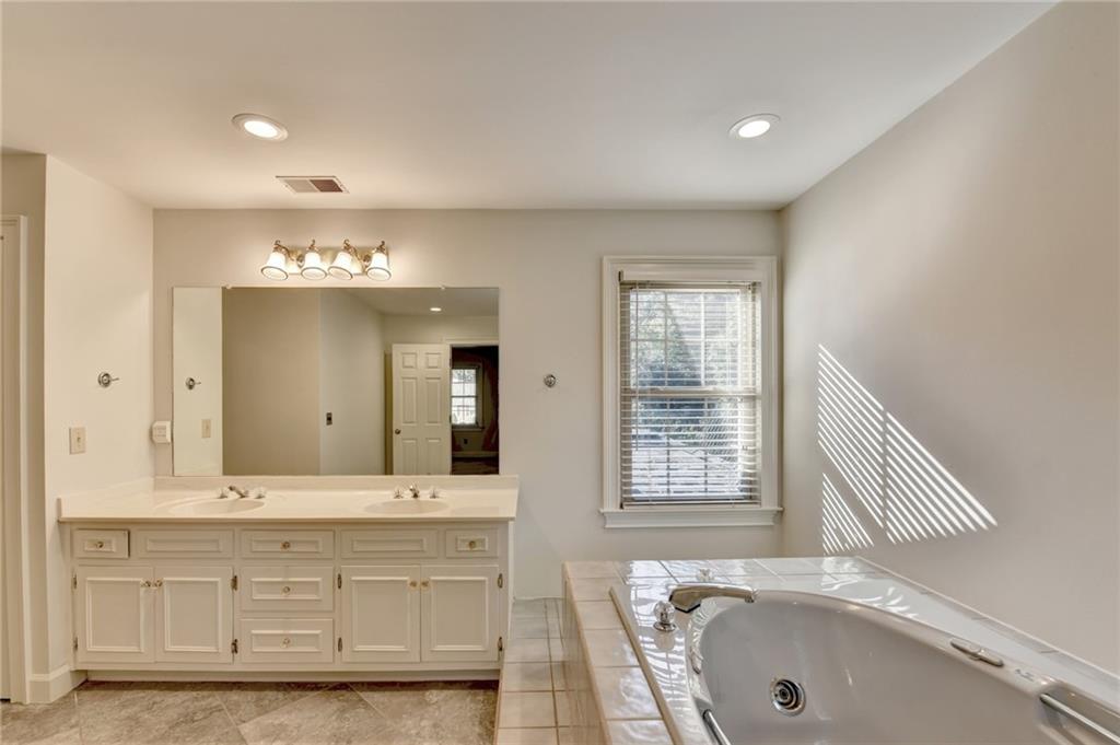 2859 Village Court Gainesville, GA 30506 - Photo 16 of 27 a bathroom with a bathtub a double vanity sink and a mirror