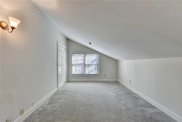 an empty room with a chandelier fan and windows