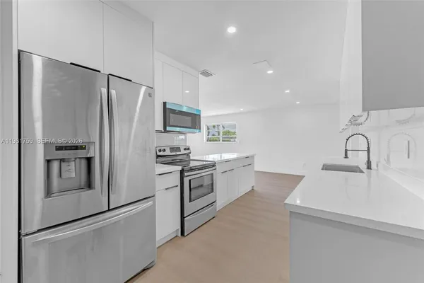 a kitchen with white cabinets and stainless steel appliances