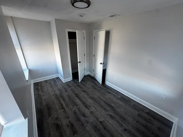 an empty room with wooden floor and entrance