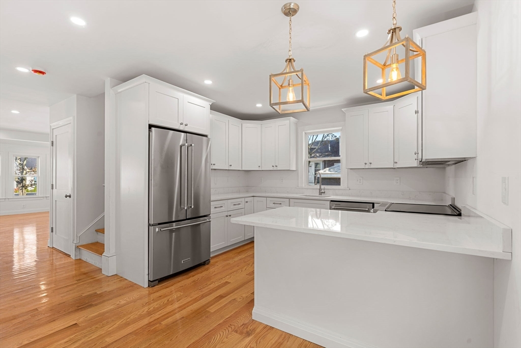 29 Willson Street Salem, MA 01970 - Photo 15 of 41 a kitchen with stainless steel appliances granite countertop a refrigerator a sink dishwasher a microwave oven a stove and white cabinets with wooden floor