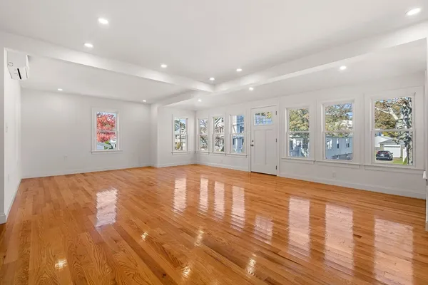 a view of an empty room with window and wooden floor