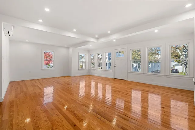 a view of an empty room with window and wooden floor