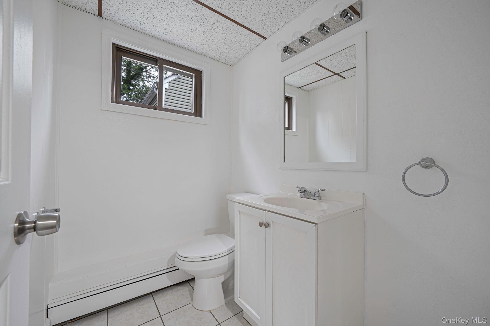 813 Windmill Avenue West Babylon, NY 11704 - Photo 23 of 32 a bathroom with a toilet sink vanity and mirror