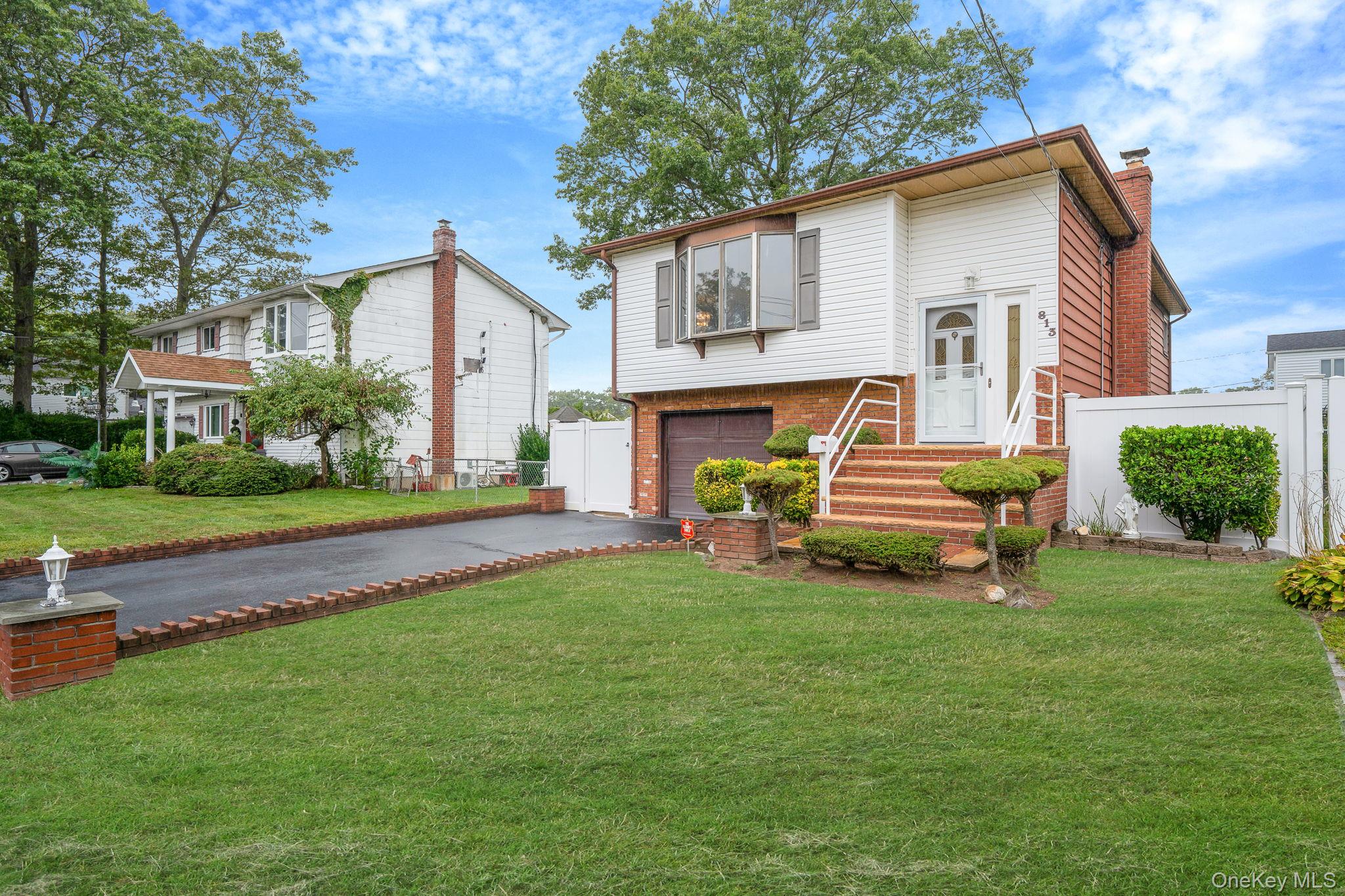 813 Windmill Avenue West Babylon, NY 11704 - Photo 3 of 32 a white house that has a small yard and couches chairs with wooden fence