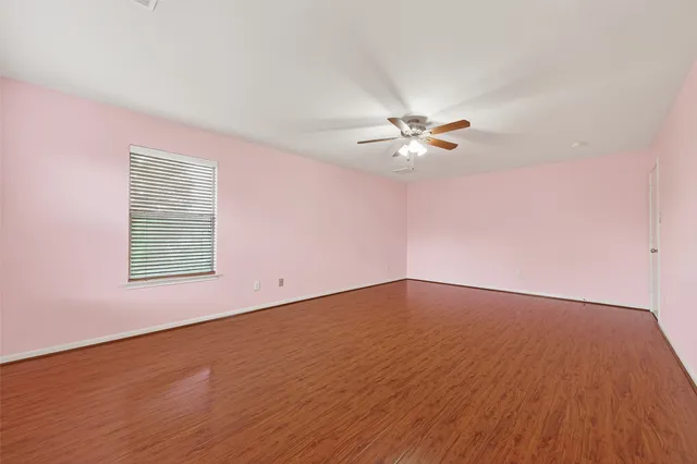 a view of an empty room with a window and wooden floor