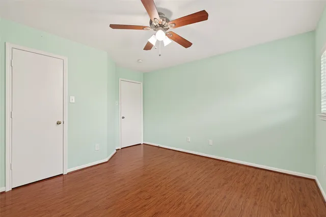 an empty room with wooden floor ceiling fan and a ceiling fan