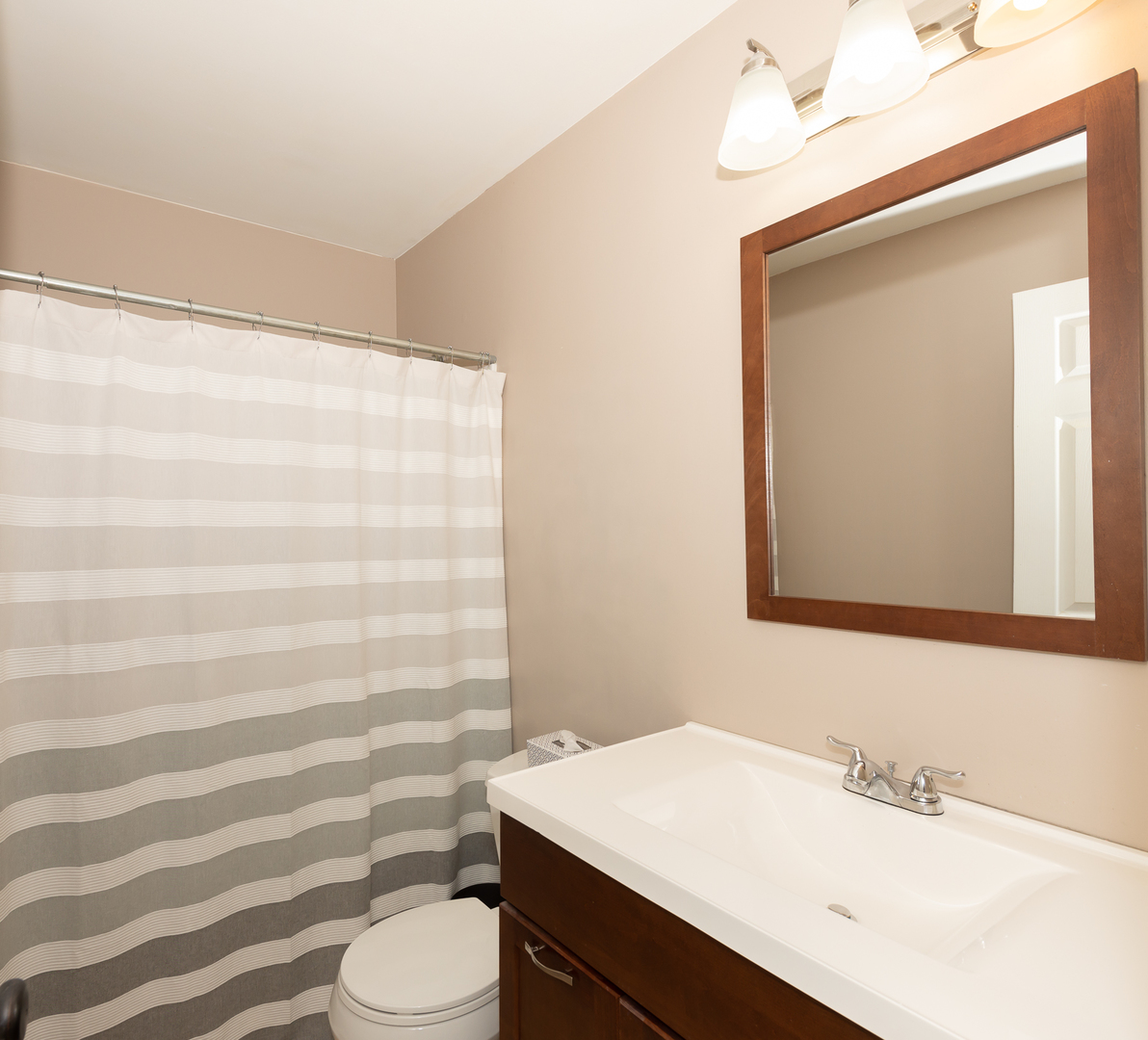 322 Rodenburg Road Roselle, IL 60172 - Photo 7 of 17 a bathroom with a sink a toilet a mirror and shower curtain