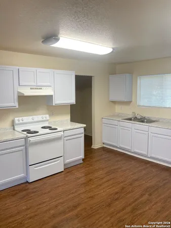 a kitchen with a white stove top oven sink and cabinets