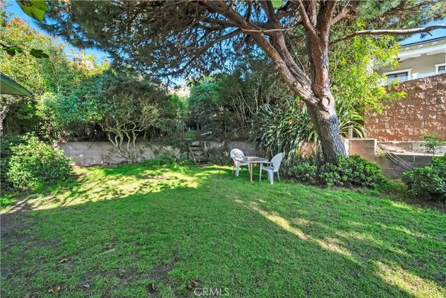 a view of backyard with table and chairs and large trees
